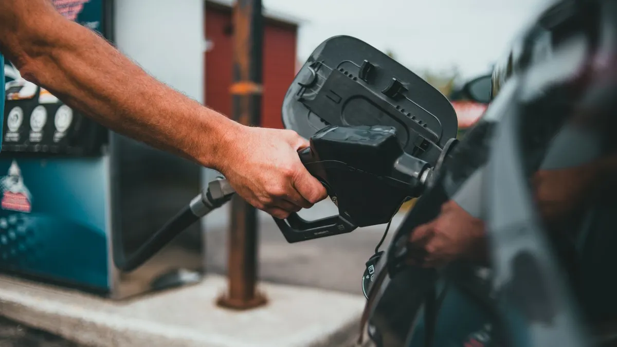 Driver refuelling a car with a fuel nozzle at an auto service gas station pump