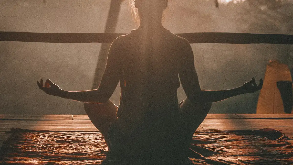 Person practising yoga at sunrise, representing calm optimism and positive thinking for prosperity