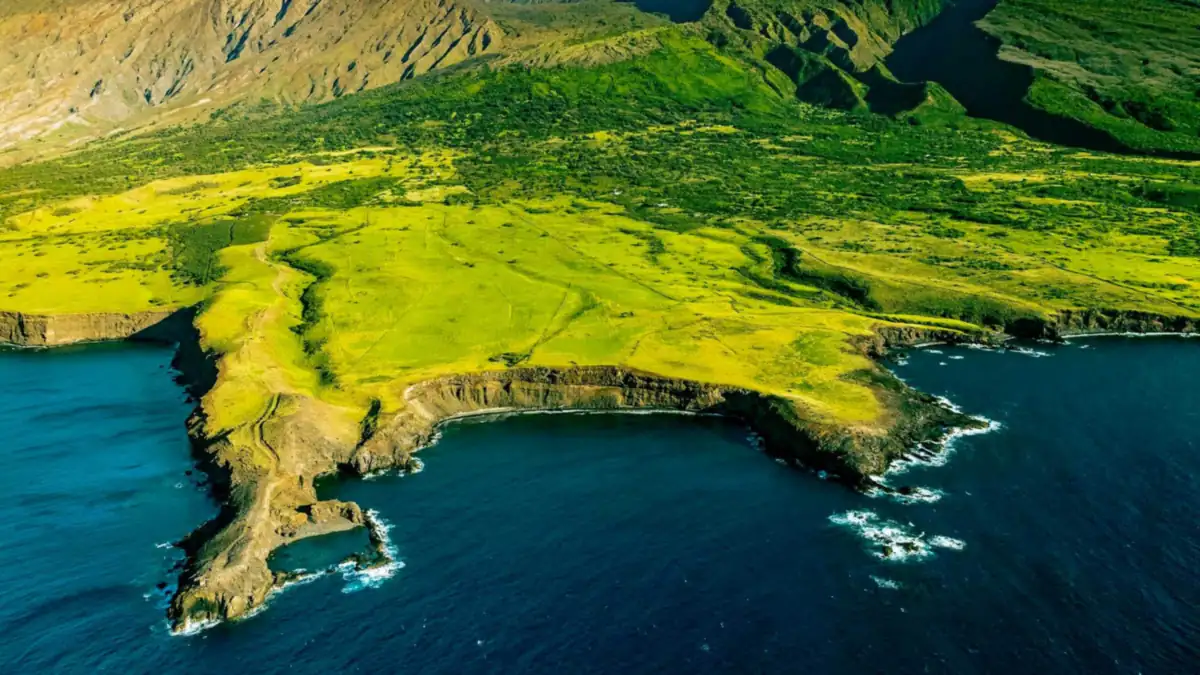 Aerial view of green coastal cliffs and deep blue ocean on a Maui helicopter tour route toward Molokai